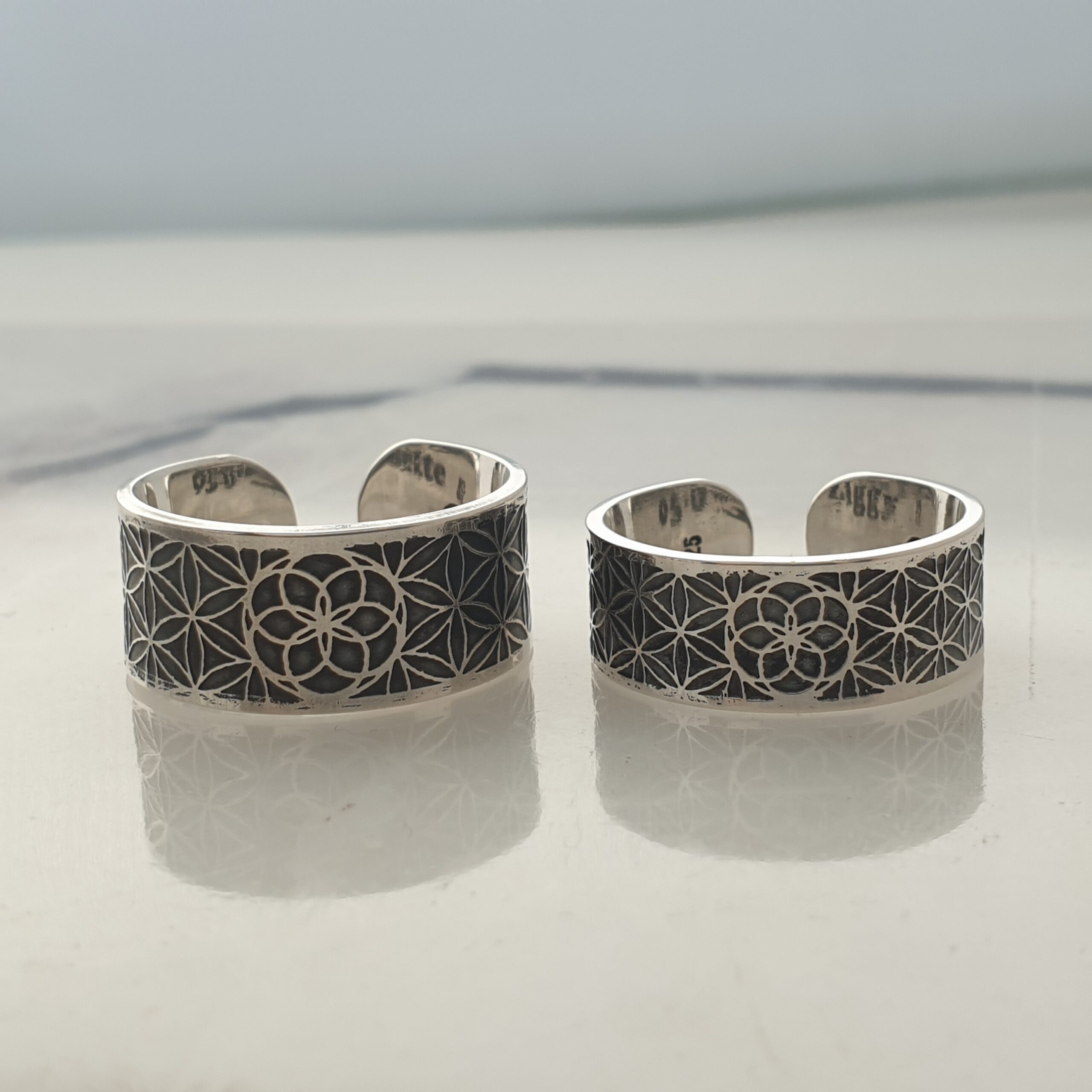 a pair of sterling silver wedding rings, etched with sacred geometry patterns