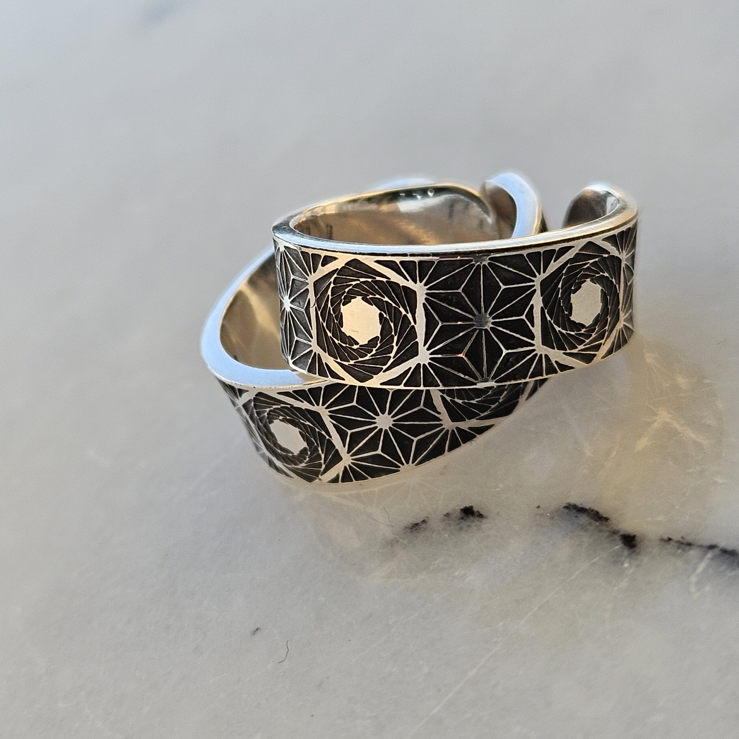 a pair of sterling silver wedding rings, etched with sacred geometry patterns