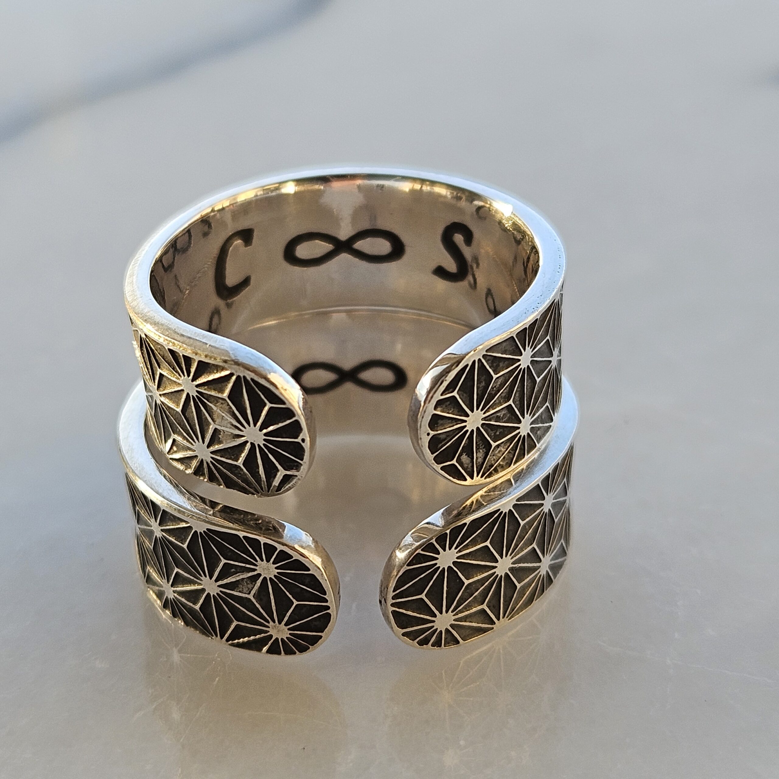 a pair of sterling silver wedding rings, etched with sacred geometry patterns